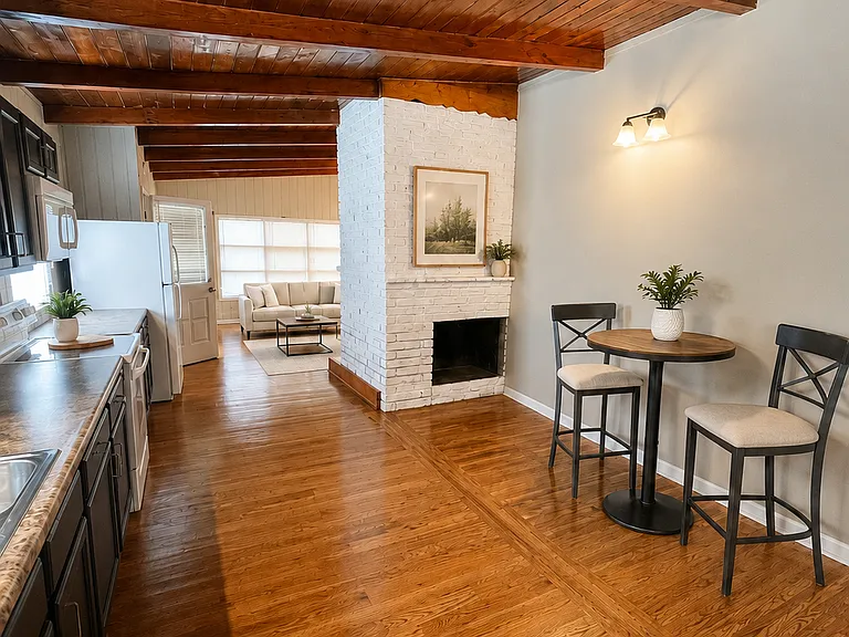 Virtually staged to illustrate possible dining placement; furnishings and decor are not included. Open view toward the decorative fireplace and living room.