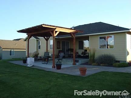 Back of home : U-shaped covered porch, step down patio with brick pavers and pergola