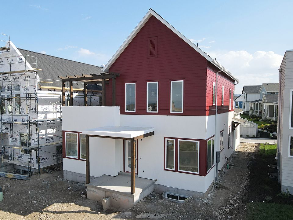 A two-story house with a red upper section and white lower section is under construction. The front
