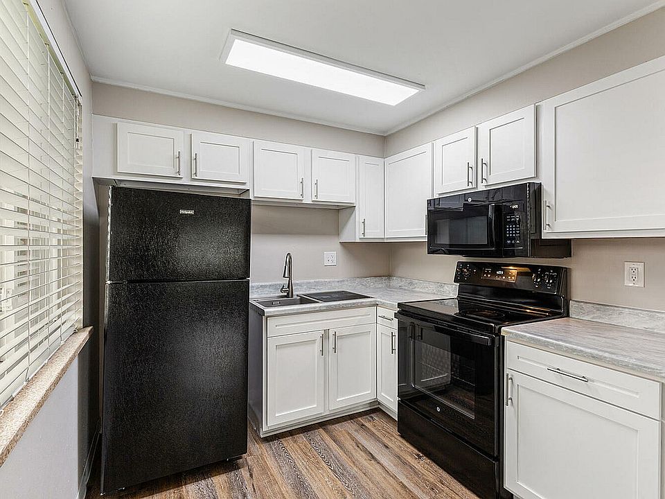 Modern kitchen featuring sleek black appliances, white cabinetry, and stylish wood flooring.