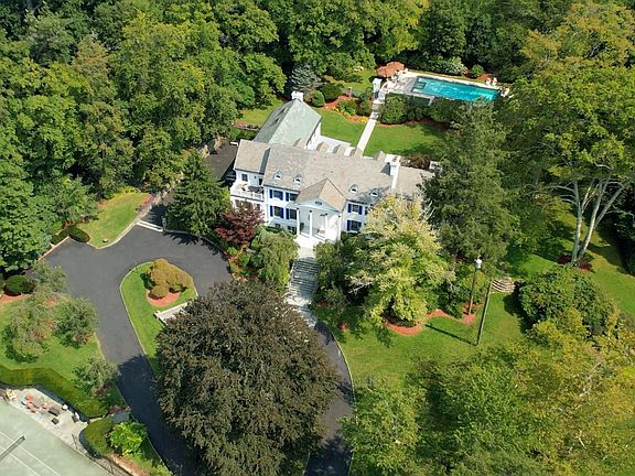 Aerial view showcases the spectacular 4-acre property with a tennis court, pool, pool house and sweeping circular driveway.