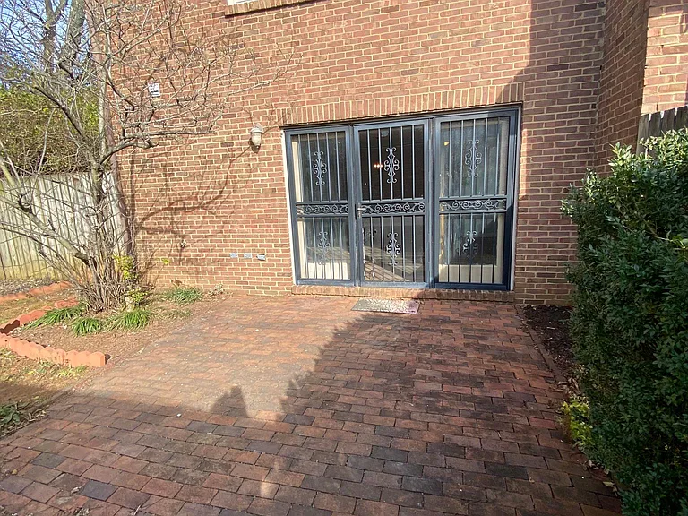 Enclosed brick courtyard separates townhome from two-car garage. Because this is an end-unit, the courtyard space is very large and there's plenty of grass and landscaping around the brick.