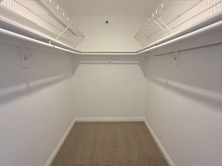 Walk-in closet with built-in shelving and hanging space.