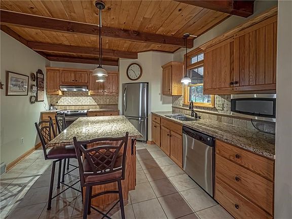 A bright chef's kitchen features abundant cabinetry, endless granite counter space complimented with a custom back splash, stain