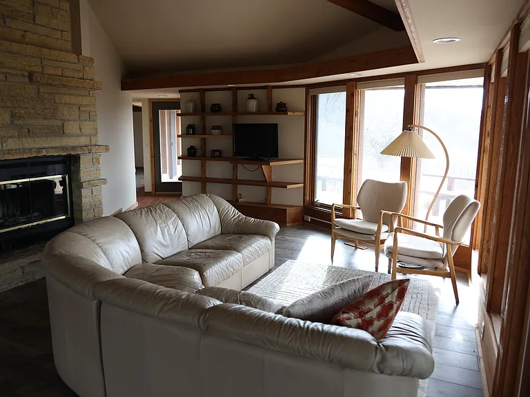 A warm and inviting space featuring a beautiful stone fireplace, built-in shelving, and large windows that bring in natural light.