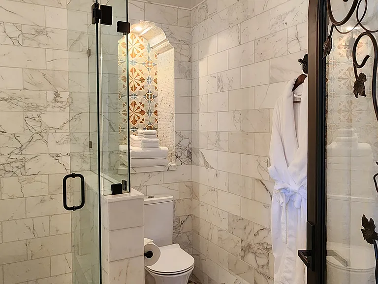 bathroom with calacatta shower and wrought iron light fixtures