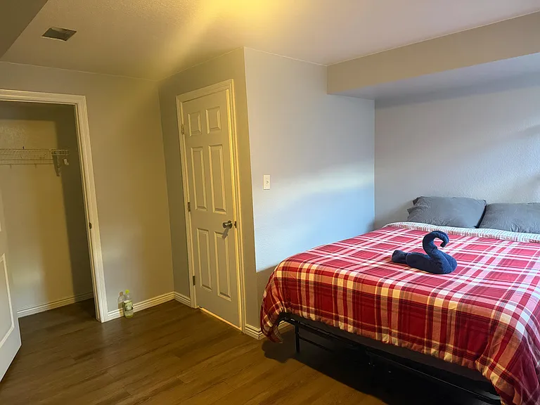 Furnished bedroom with a queen-size bed, durable flooring, and a walk-in closet with shelving for easy storage.
