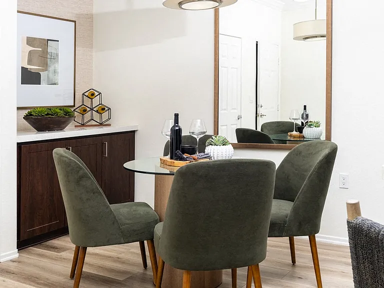 Cozy Dining Area with Glass Table, Velvet Chairs, and Accent Mirror