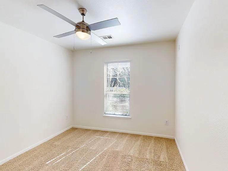 Spacious apartment bedroom with plush carpet flooring.