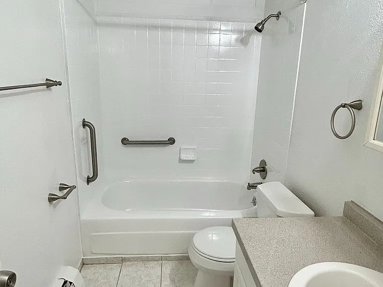 Pristine bathroom featuring sparkling white tiles, a sleek bathtub, and modern fixtures for a luxurious feel.