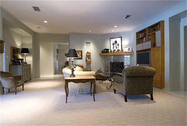  A second view of the great room, looking toward the open kitchen, showing corner fireplace and big-screen television shelf with cabinets and bookshelves.