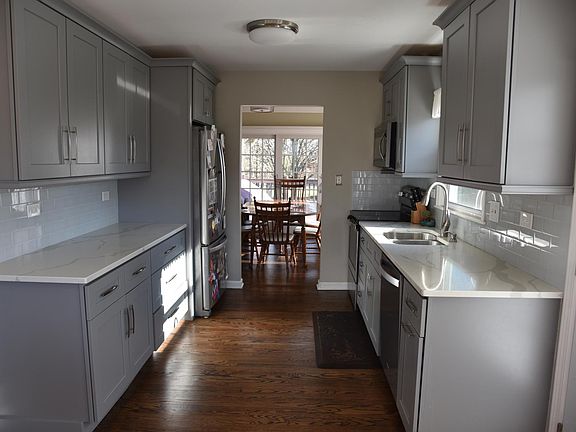 View of Kitchen into the dining room and out the sliding door to the large back deck. Completely Remodeled in 2018 with New Kitchen: 19 ft x 15 ft - New Cabinets, quartz counter tops, all appliances, floors, backsplash and lighting.