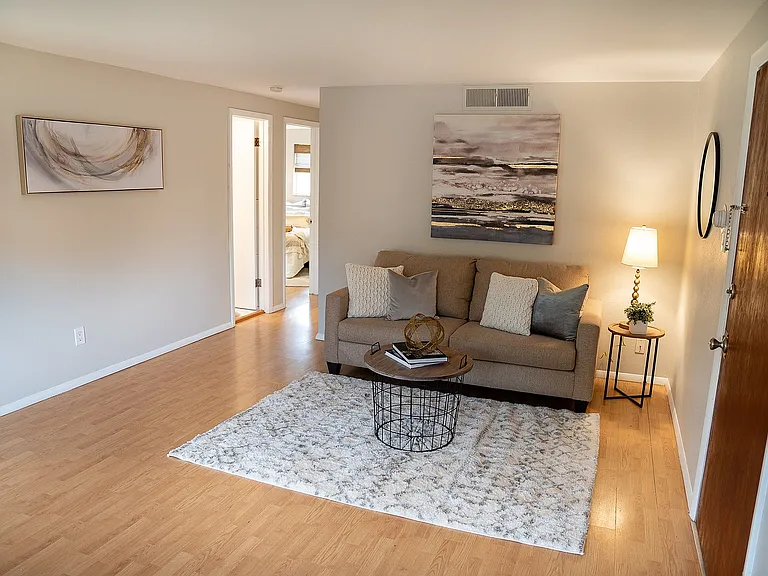Cozy living room with modern decor, featuring a comfortable sofa, stylish artwork, and soft lighting on wooden flooring.