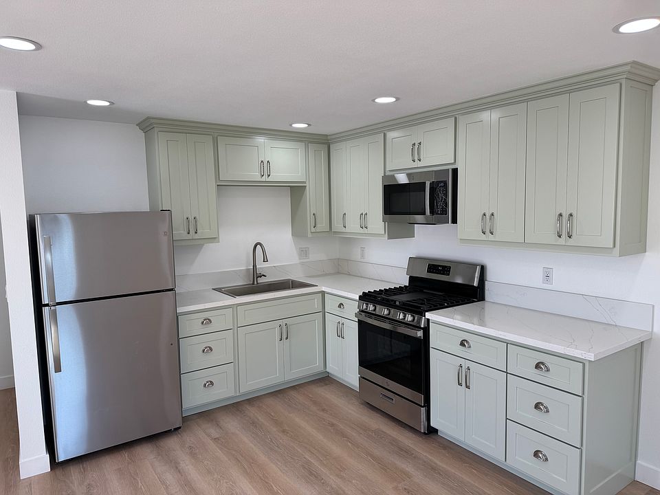 Sage green modern kitchen with new white quartz countertops.