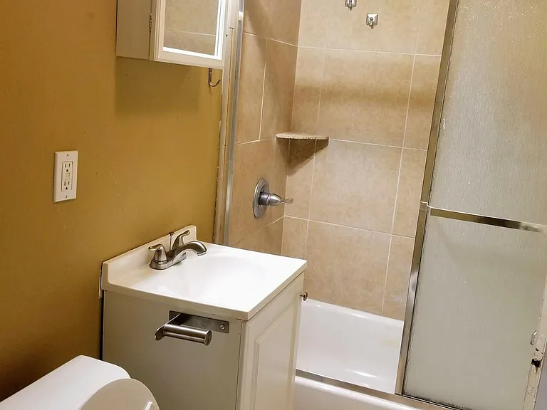 Bathroom with toilet, sink, and full shower with tub