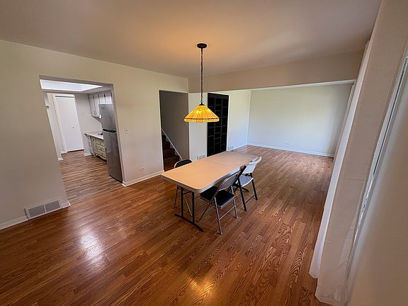 Same dining and living room combo., Entry to kitchen, stairway to 2nd floor, and built in black bookcase.