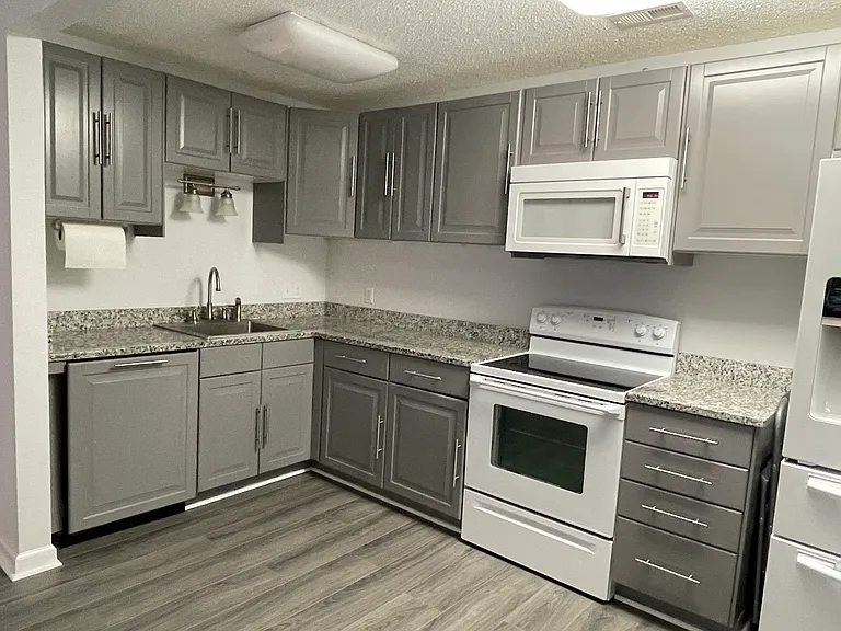 Kitchen area includes stove, microwave and exhaust fan, dishwasher, refrigerator and large storage cabinet.