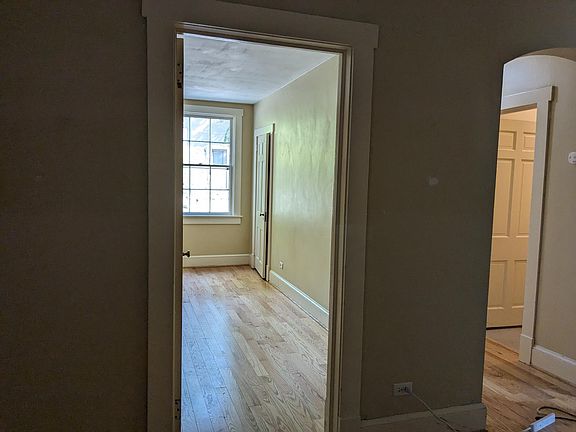 From living room, looking into front bedroom and hallway with door to the bathroom shown open.