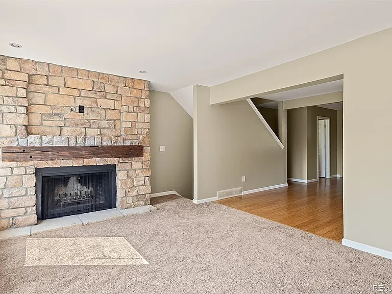 Living area with natural light and fireplace next to basement stairs.