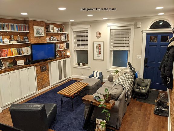 Amazing living room with custom built in shelving and storage, and beautiful exposed brick.