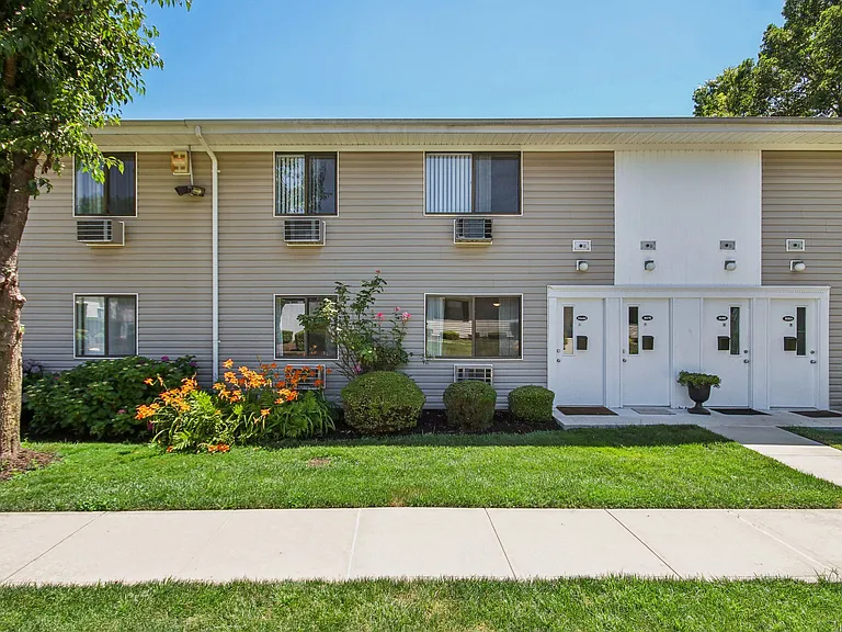Exterior view of apartment building with green grass and trees