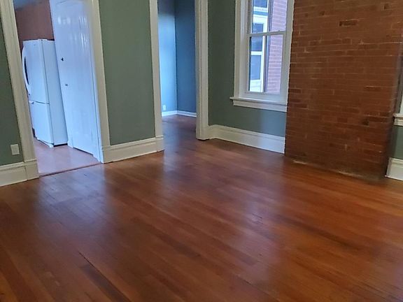 Huge living room with stunning wood floors and exposed brick.