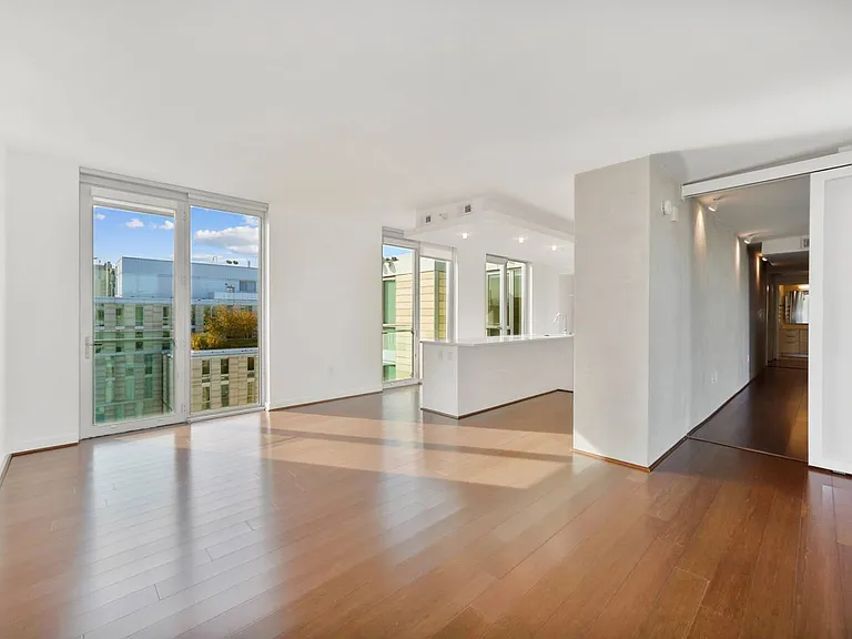 Bask in natural light and modern elegance in this open-concept apartment, featuring rich hardwood floors and floor-to-ceiling windows.