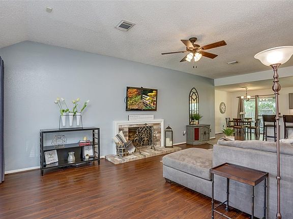 The foyer flows into the stunning open-concept living space, with a multi-colored brick fireplace framed by pearl-covered crown molding.