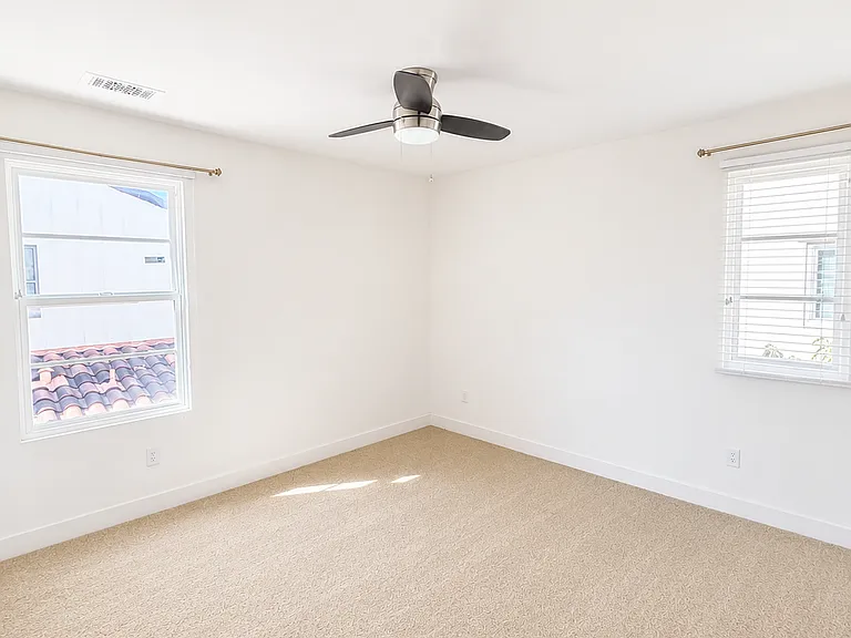 Light-filled secondary bedroom with windows on two sides and ample living space