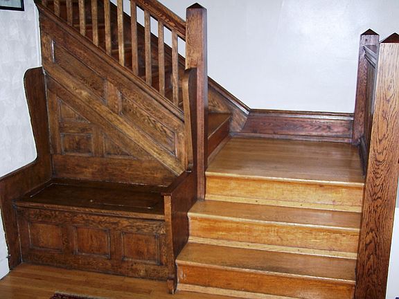The bench seat and restored woodwork highlight the stairs to the upper level.
