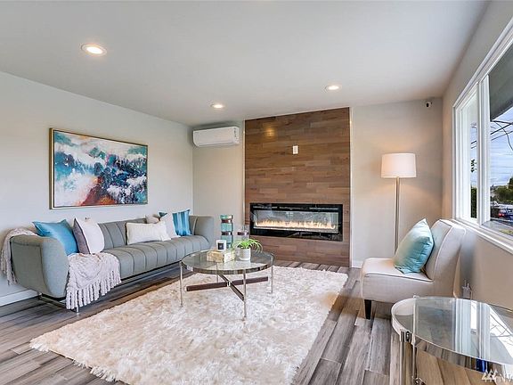 Lovely living room adorned with custom wood-accent wall, electric fireplace w/multi-color flames, 1 of 7 ductless mini-splits and more! You can adjust the lumen levels of the living room's recessed lighting!