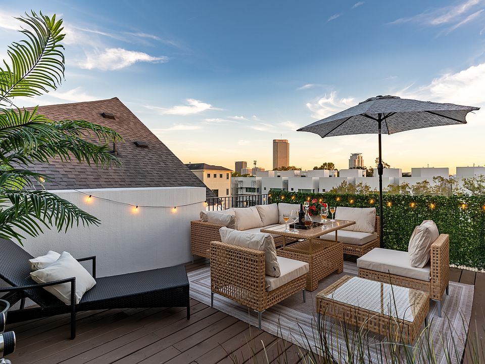 A rooftop patio with comfortable seating area, city view and ambient lighting