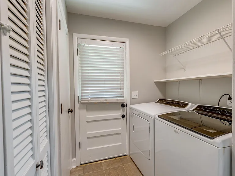 Laundry room with washer and dryer, door leading to backyard.