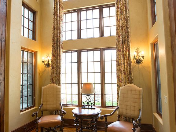 Cozy furniture niche surrounded by sunlit windows offering views of the park-like backyard is the perfect setting to display holiday decorations.