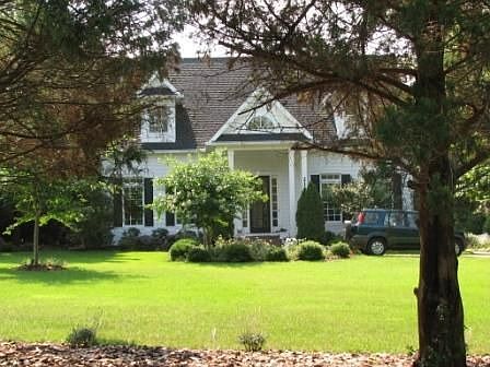 Tucked into the trees, a magnificent Cape Cod which is larger than she looks!