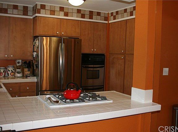 Kitchen with stainless steel oven, gas cooktop and custom tile open to dining room.