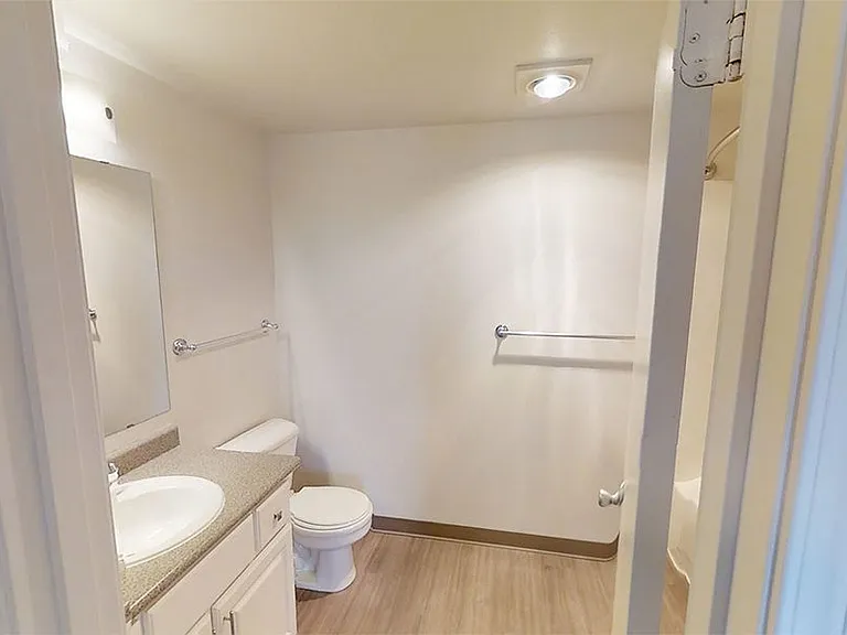 Apartment bathroom with wood-style flooring.