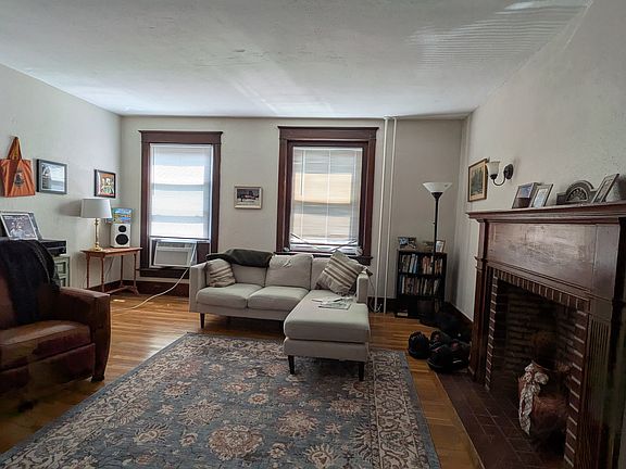 Large living room with huge windows overlooking Main St with an ornamental, original fireplace