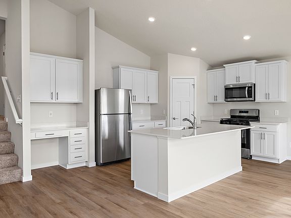 The kitchen has stainless steel appliances and plank flooring.