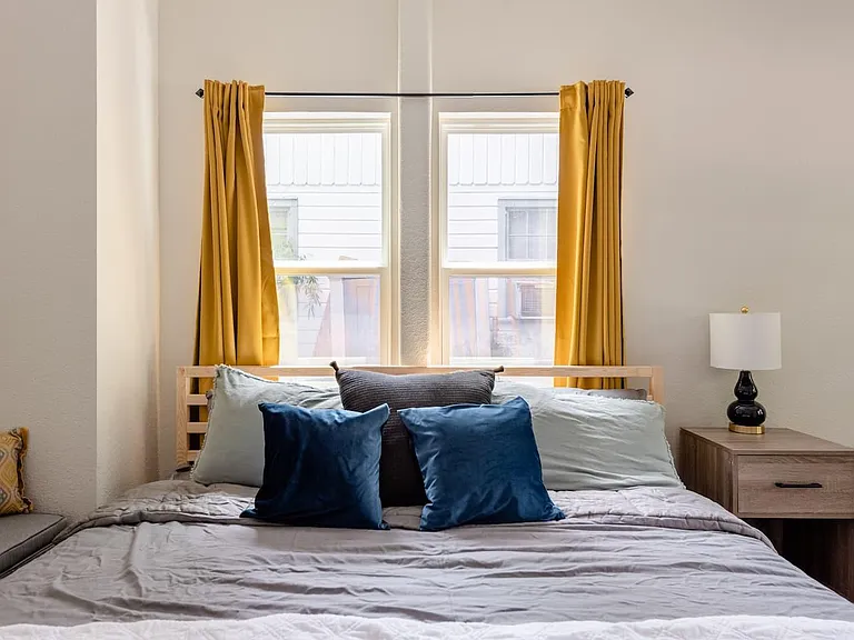 Large bedroom with a king bed; it also has a desk with a chair that faces towards a beautiful window.