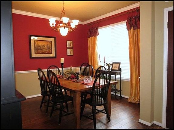 Formal dining room has hand scrapped wood floors, crown molding, chair rail and custom paint.