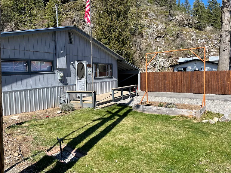 Front of home, yard with garden box for tenant use. Gravel area for additional parking