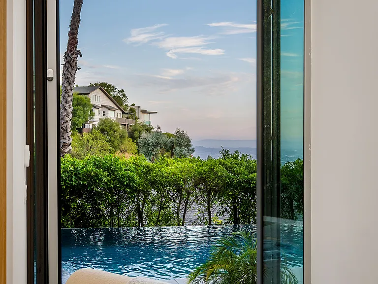 The downstairs lounge features floor-to-ceiling windows that open to the pool, an oversized smart TV, plush seating for four, and a curated selection of board games_perfect for family fun and relaxed evenings together.