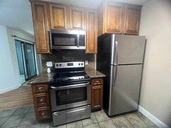 Kitchen with electric stove, oven, microwave and refrigerator.