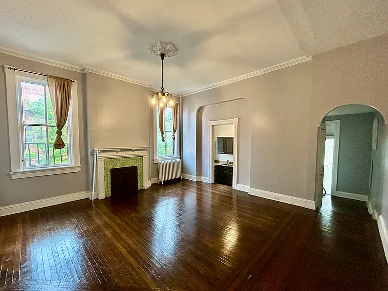 Large living room with high ceilings, large windows, fresh paint, and newly sanded and stained hardwood floors.