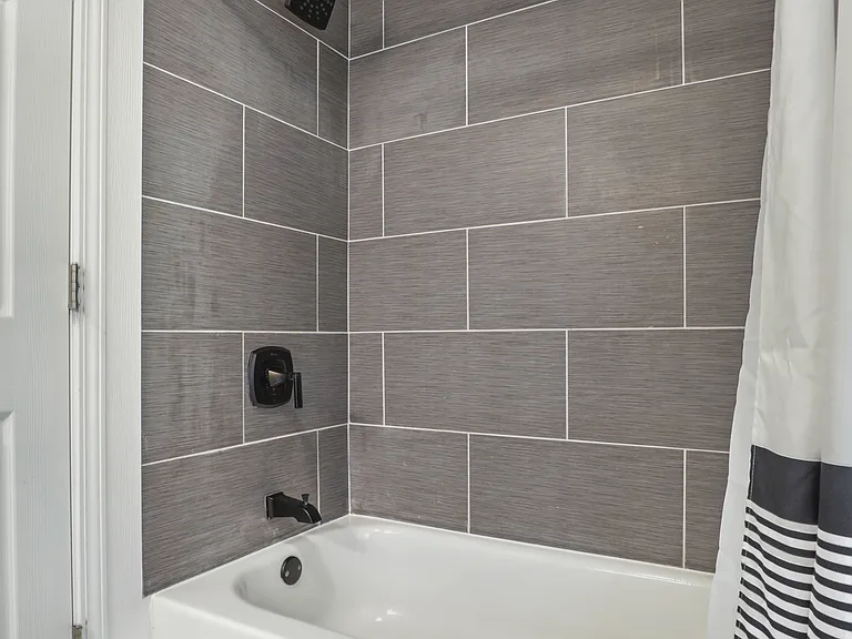 Bathroom off the kitchen, bath tub, tile floors and shower.