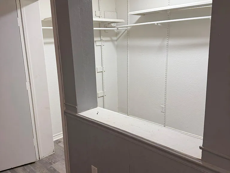 Built-in closet nook with adjustable shelving and hanging rods provides convenient storage off the main hallway.