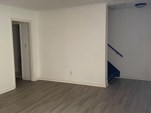 Living room with access to half bathroom and staircase.