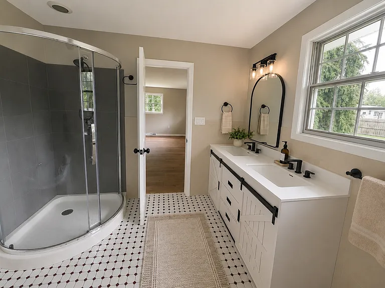 Bright, updated primary bathroom with a double vanity, soaking tub, and walk-in glass shower.