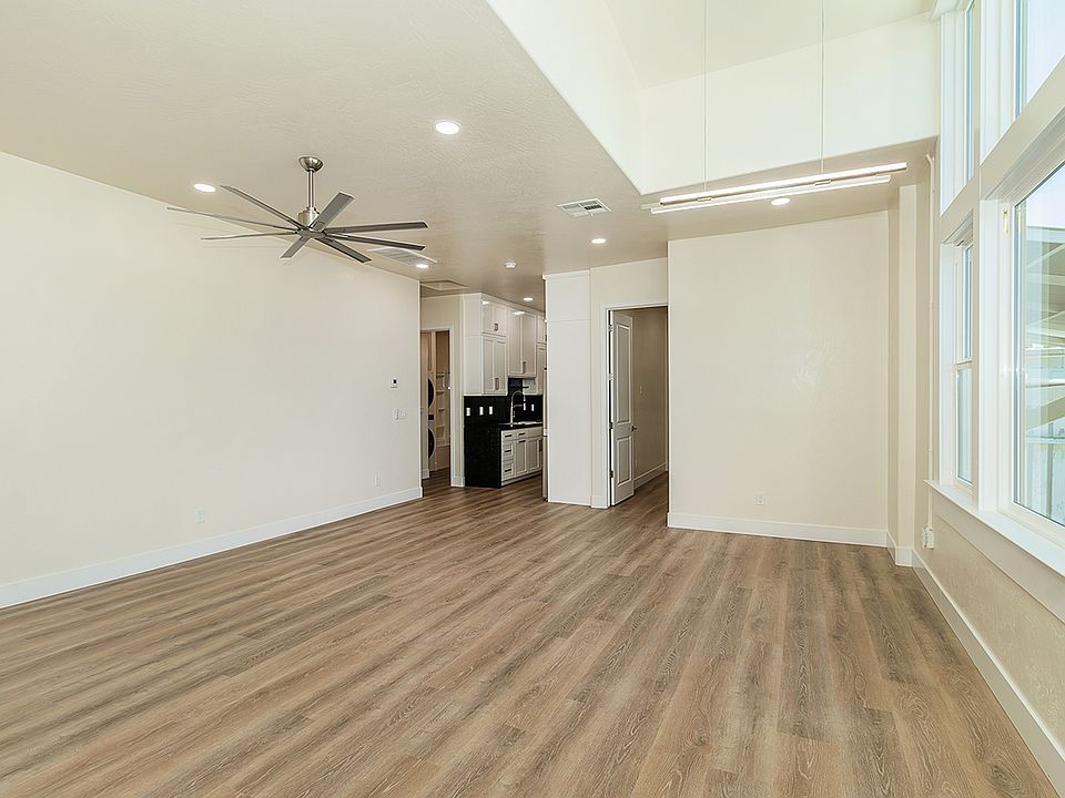 Large High Vaulted Ceiling with Custom Fan, Amazing Large Windows, Luxury Vinyl Plank Flooring, And Automatic Roll Down Shades.